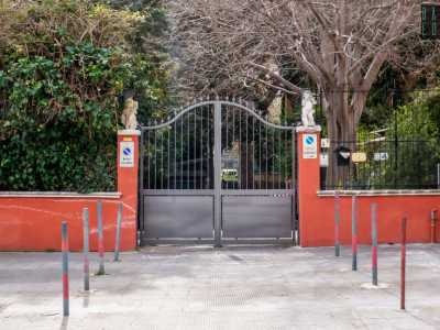 ...si trova un moderno cancello grigio posto tra due pilastri rossi...